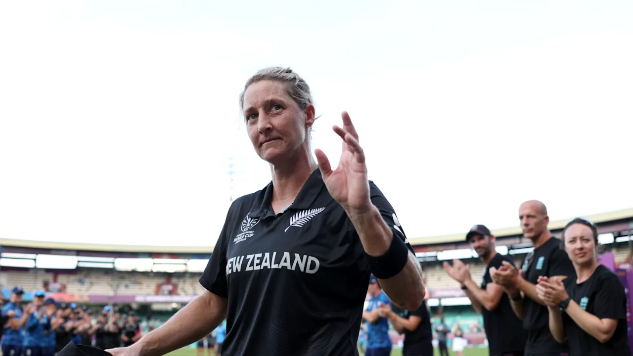 New Zealand cricketer Sophie Devine waving to the crowd at a stadium as teammates applaud