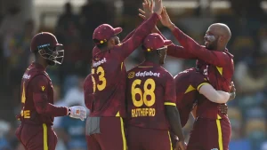 West Indies men's cricket team celebrating a wicket in their maroon ODI jerseys during an international match.