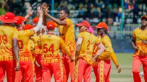 Zimbabwe men's cricket team celebrating on the field during a match in yellow and red uniforms