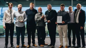 Winners of the 2025 ECB Grounds Manager of the Year Awards pose with trophies and certificates at a cricket stadium.