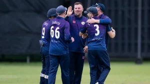 Cricket Scotland men's team players celebrate a wicket during a match in purple and navy team kit