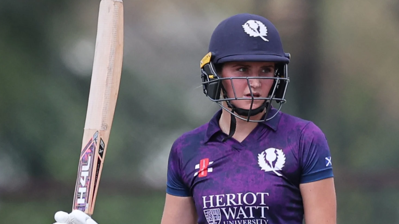 Cricket Scotland women’s team player in purple Heriot-Watt University kit holding a cricket bat during a match