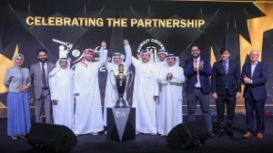 Officials from DP World ILT20 and Kuwait Cricket celebrate partnership announcement with trophy on stage.