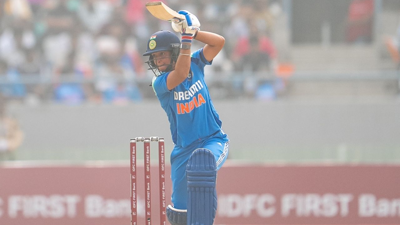 India women's cricket team captain Harmanpreet Kaur plays a shot during a match, wearing the blue national jersey, with IDFC FIRST Bank branding on the stumps and boundary boards.