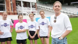 England cricketer Heather Knight with young girls wearing Knight-Stokes cricket shirts during a grassroots event at a stadium.