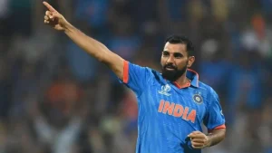 Indian fast bowler Mohammed Shami celebrates after taking a wicket, pointing to the crowd during a Cricket World Cup match in India’s blue jersey.