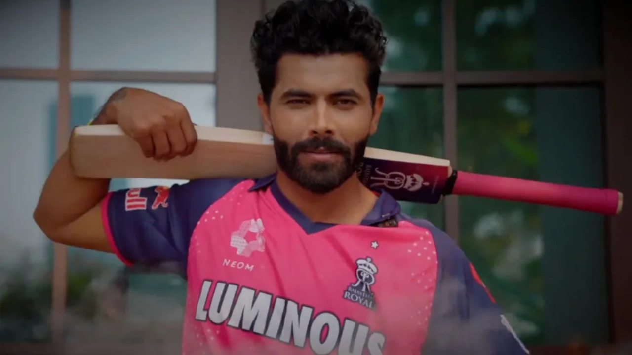 Ravindra Jadeja poses confidently with a bat on his shoulder while wearing the Rajasthan Royals 2025 jersey in a promotional shoot.