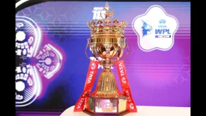 The Tata WPL 2025 trophy on display with red ribbons, showcased against a purple Women's Premier League backdrop