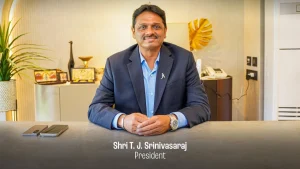 TNCA President T.J. Srinivasaraj seated at a desk, smiling in a formal setting