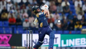 Tom Kohler-Cadmore of Deccan Gladiators playing a powerful shot during a T10 League 2025 match, with crowd in background