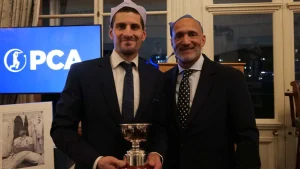 Benny Howell holding a trophy with Mark Butcher at a PCA awards ceremony, with the PCA logo in the background.