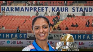 Indian cricketer Harmanpreet Kaur holding the ICC Women’s World Cup trophy in front of a stadium stand named after her