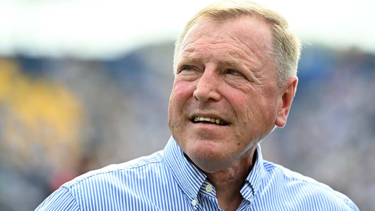 Hugh Morris looking away with a thoughtful expression at a stadium event