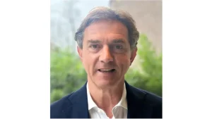 Portrait of Huib van Walsem, CEO of Cricket Netherlands, in a suit with greenery in the background