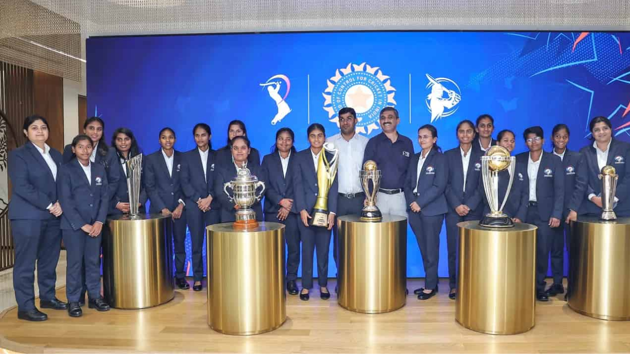 India Blind Women’s Cricket Team posing with the T20 World Cup trophy and other awards in front of the BCCI backdrop.