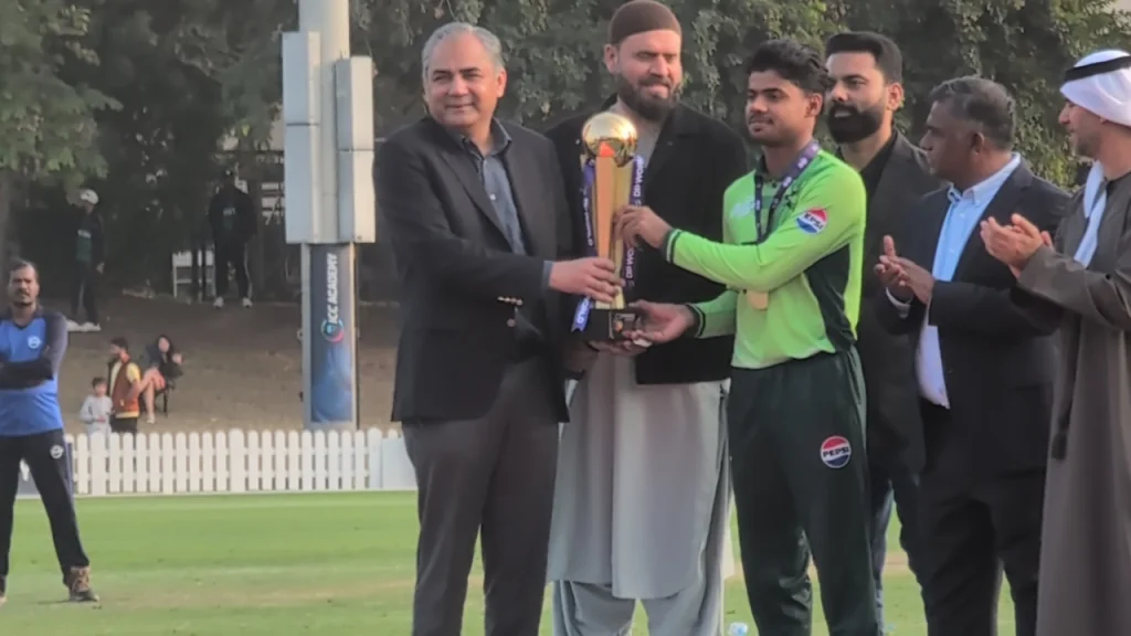 ACC President and PCB Chairman Mohsin Naqvi presenting the trophy to a Pakistan U19 player after winning the Asia Cup 2025, with officials applauding in the background.