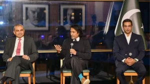 Mohsin Naqvi, Ramiz Raja, and Wasim Akram speaking at the PSL Roadshow event in London with a Pakistan flag in the background