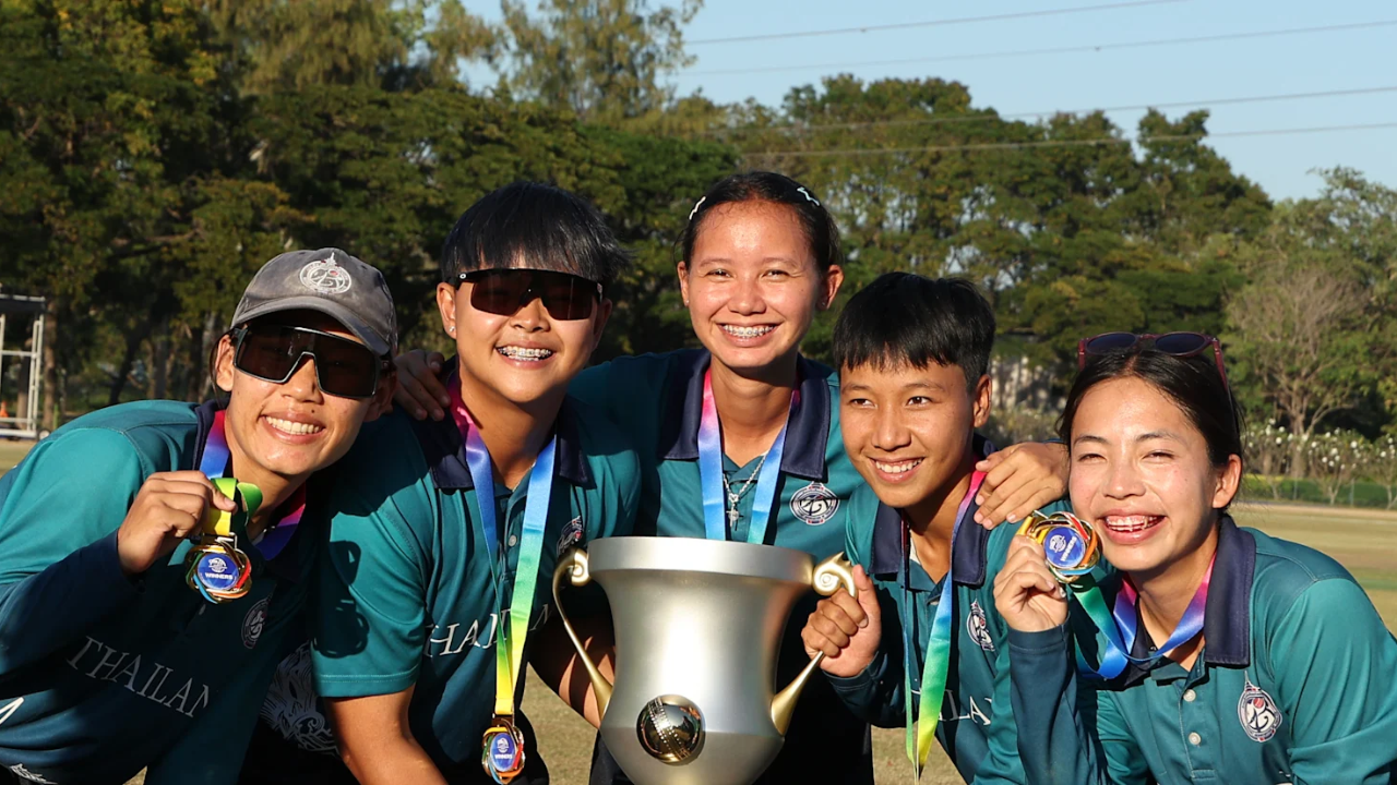 Thailand women’s cricket team players smiling and posing with winner’s trophy and medals after a tournament victory in 2025.
