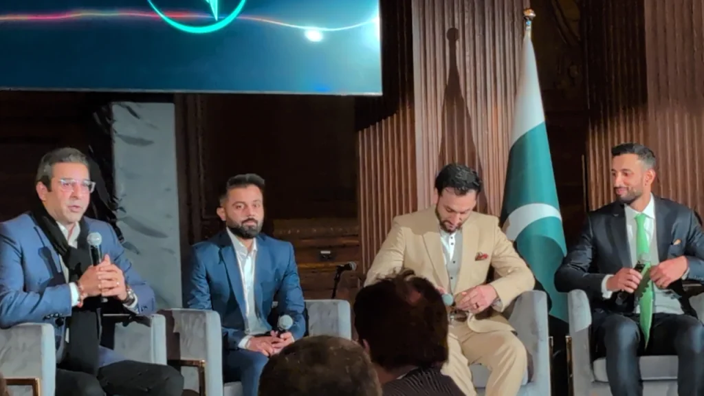 Wasim Akram, Saud Shakeel, Salman Ali Agha, and Shan Masood at the Pakistan Super League (PSL) Roadshow event in New York, seated with microphones and Pakistan flag in the background