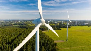 Aerial view of wind turbines generating renewable energy over green farmland and forest landscape on a clear day