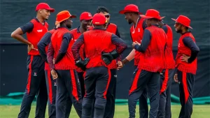 Zimbabwe domestic cricket team players in red and black uniforms huddled together during a match.