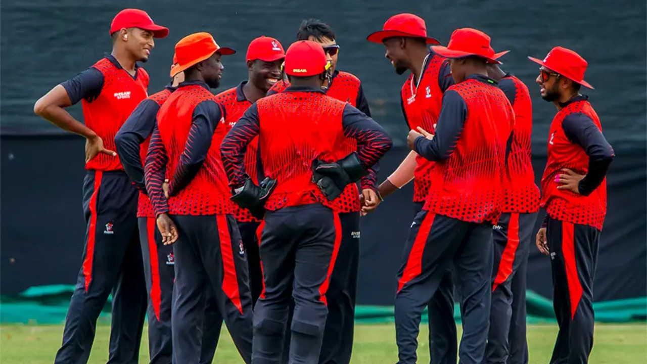 Zimbabwe domestic cricket team players in red and black uniforms huddled together during a match.
