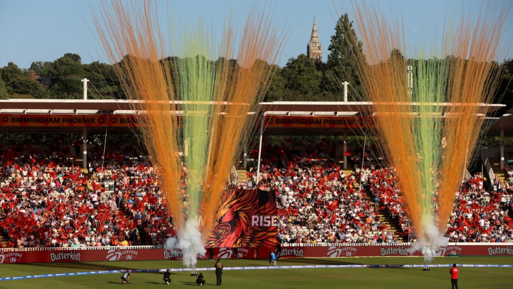 Crowd erupts with colorful pyrotechnics and banners during a Birmingham Phoenix match at Edgbaston Stadium in The Hundred tournament.