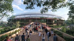 Large crowd walking towards a modern, eco-friendly stadium surrounded by lush greenery and trees on a sunny day