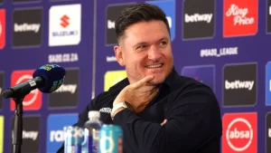 Graeme Smith at a press conference during the SA20 2026 tournament, smiling while seated in front of sponsor backdrops including Betway and Absa.