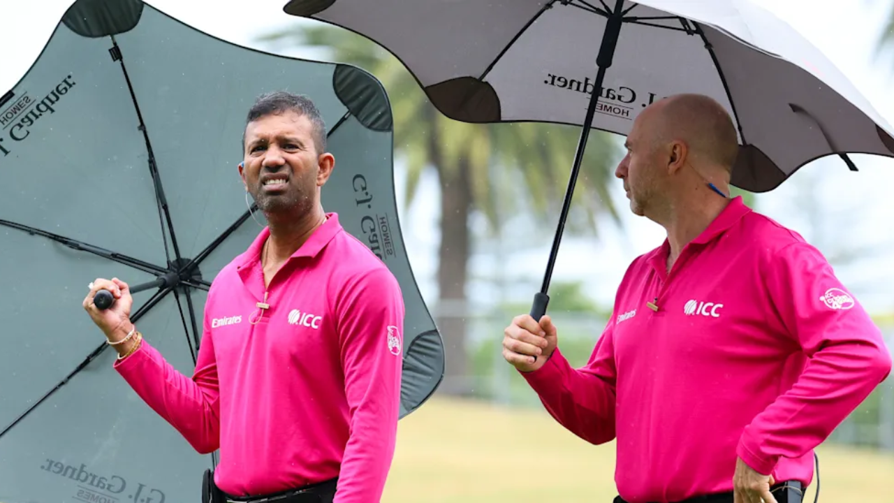 Cricket umpires Kumar Dharmasena and Wayne Knights holding umbrellas during a rain delay at an ICC match.