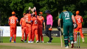 Netherlands cricket team players celebrating a wicket during a match, with the umpire and opposition batter in the frame.