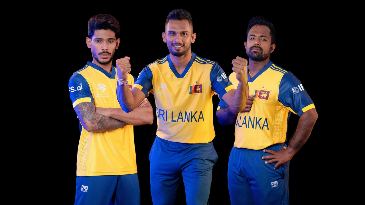 Sri Lanka cricket captain Dasun Shanaka poses with two team members in official yellow and blue T20 World Cup 2026 uniforms against a black background.