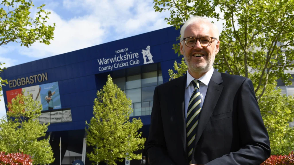 Warwickshire CCC CEO Stuart Cain standing outside Edgbaston Stadium in Birmingham, with club signage in the background.
