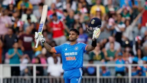 Indian cricketer Suryakumar Yadav celebrates his century against South Africa, raising his bat and helmet in front of a cheering crowd during the 2026 match.