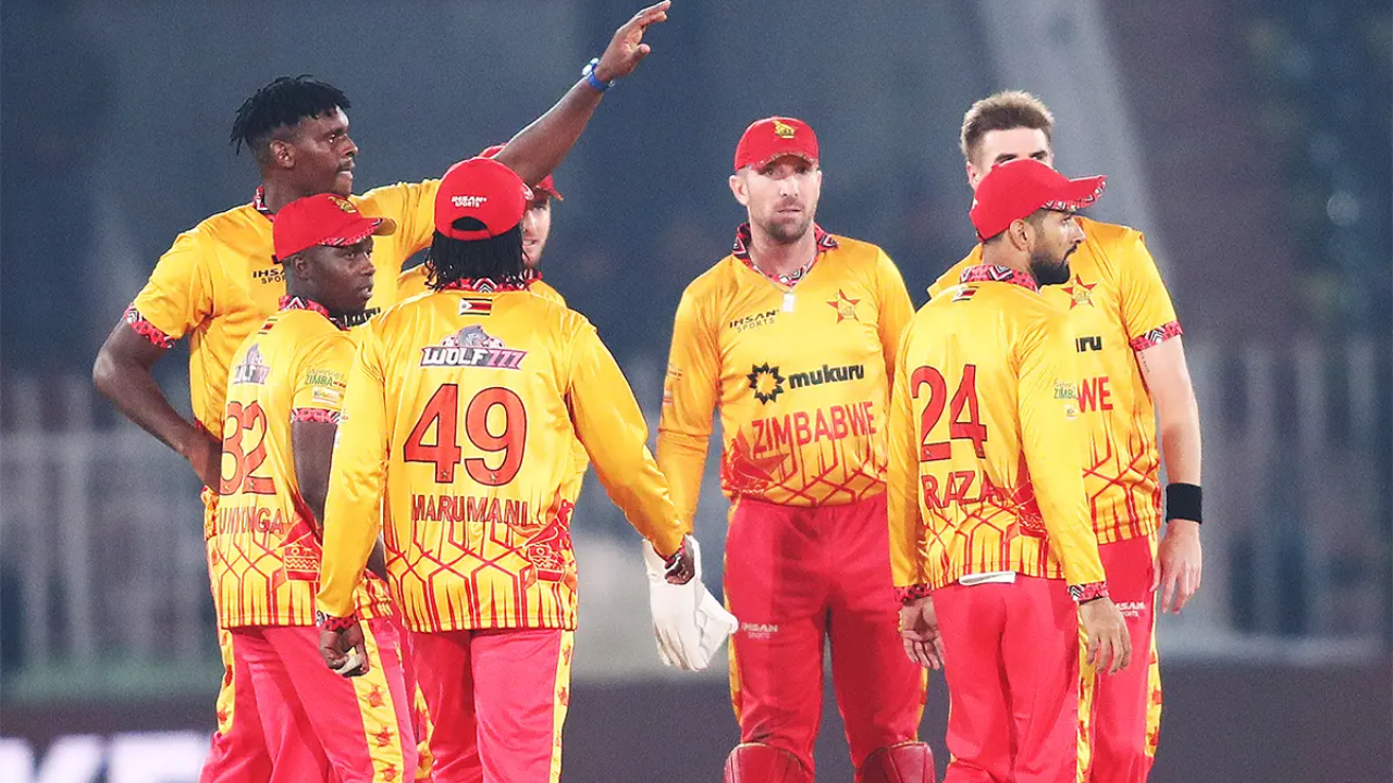 Zimbabwe cricket team players wearing yellow and red jerseys during a match, gathered in celebration on the field.