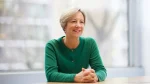 Clare Connor smiling during an interview at a desk in a modern office setting
