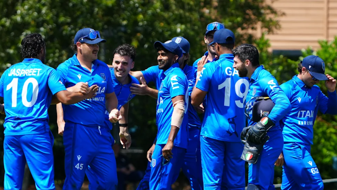 Italy men's cricket team players celebrating a wicket during a match, wearing blue jerseys
