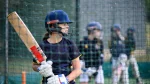 Young female cricketer batting in practice nets wearing helmet and gloves, representing the Metro Bank Women’s and Girls Cricket Collection 2025.