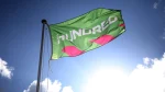 The Hundred cricket competition flag flying on a pole against a blue sky at a stadium.