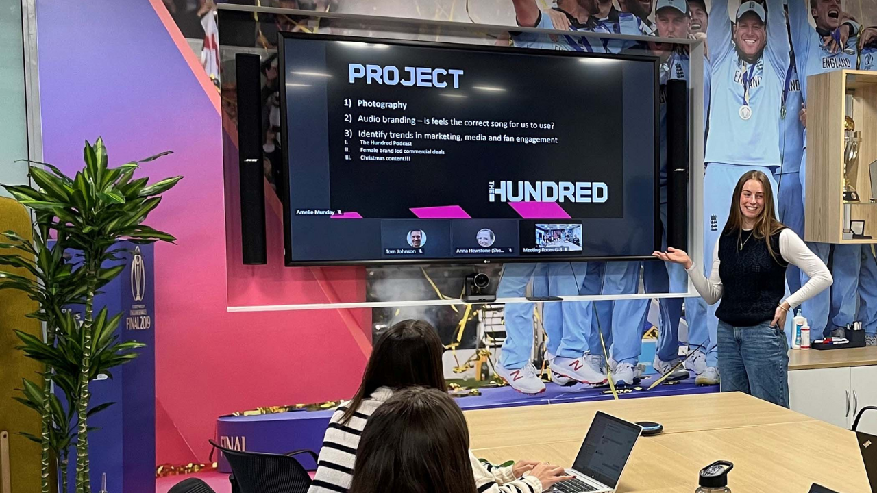 Marketing team member presenting a project on The Hundred cricket tournament at the England Cricket Board office with a screen showing project details