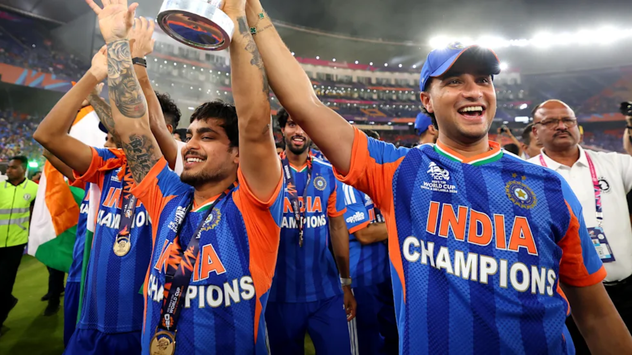 Abhishek Sharma and Ishan Kishan celebrating with the India team after winning the ICC Men’s T20 World Cup, holding the trophy during the on-field celebration.