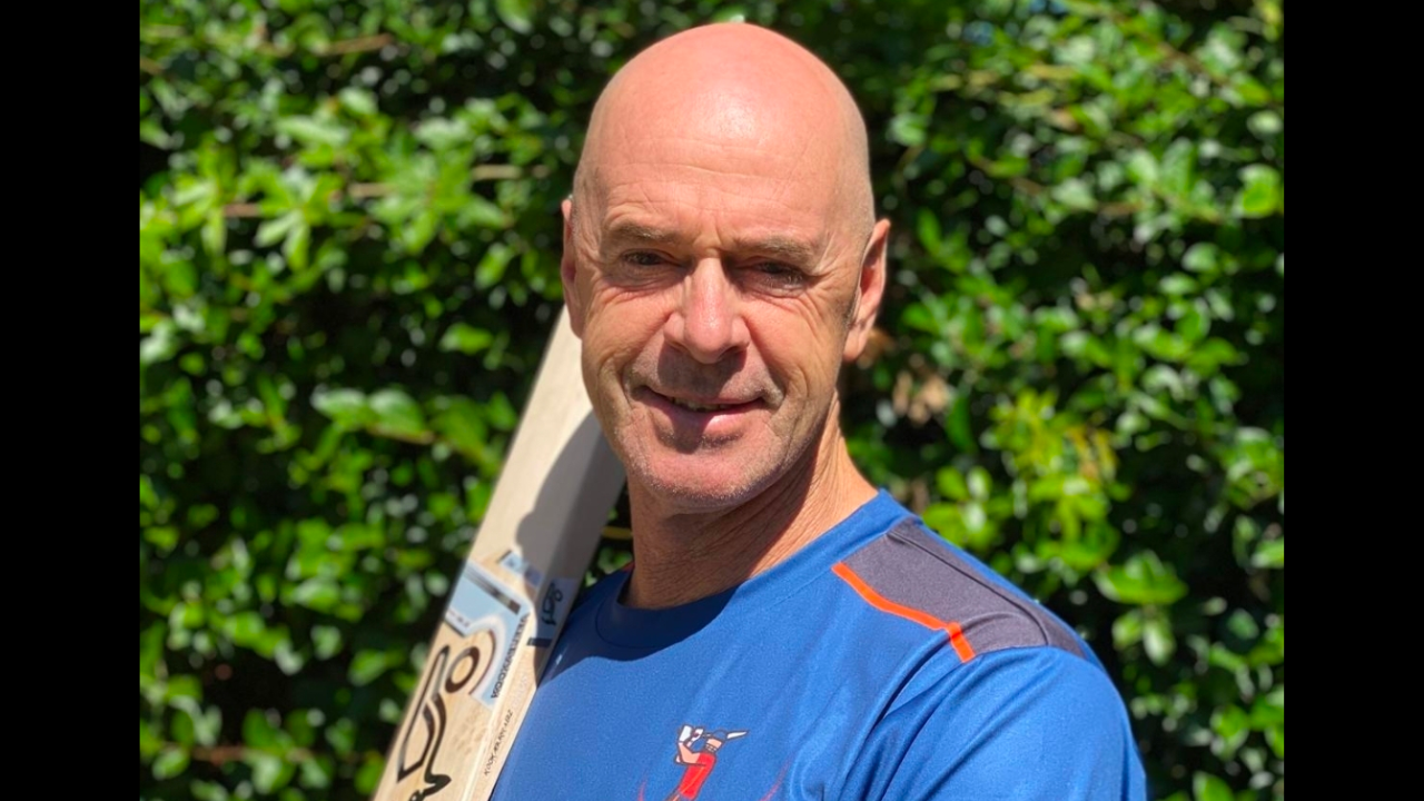 Portrait of cricket coach Jamie Siddons holding a cricket bat during a training session outdoors.