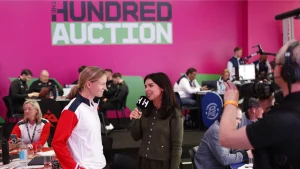 Meg Lanning being interviewed during The Hundred cricket auction with teams and media in the background.