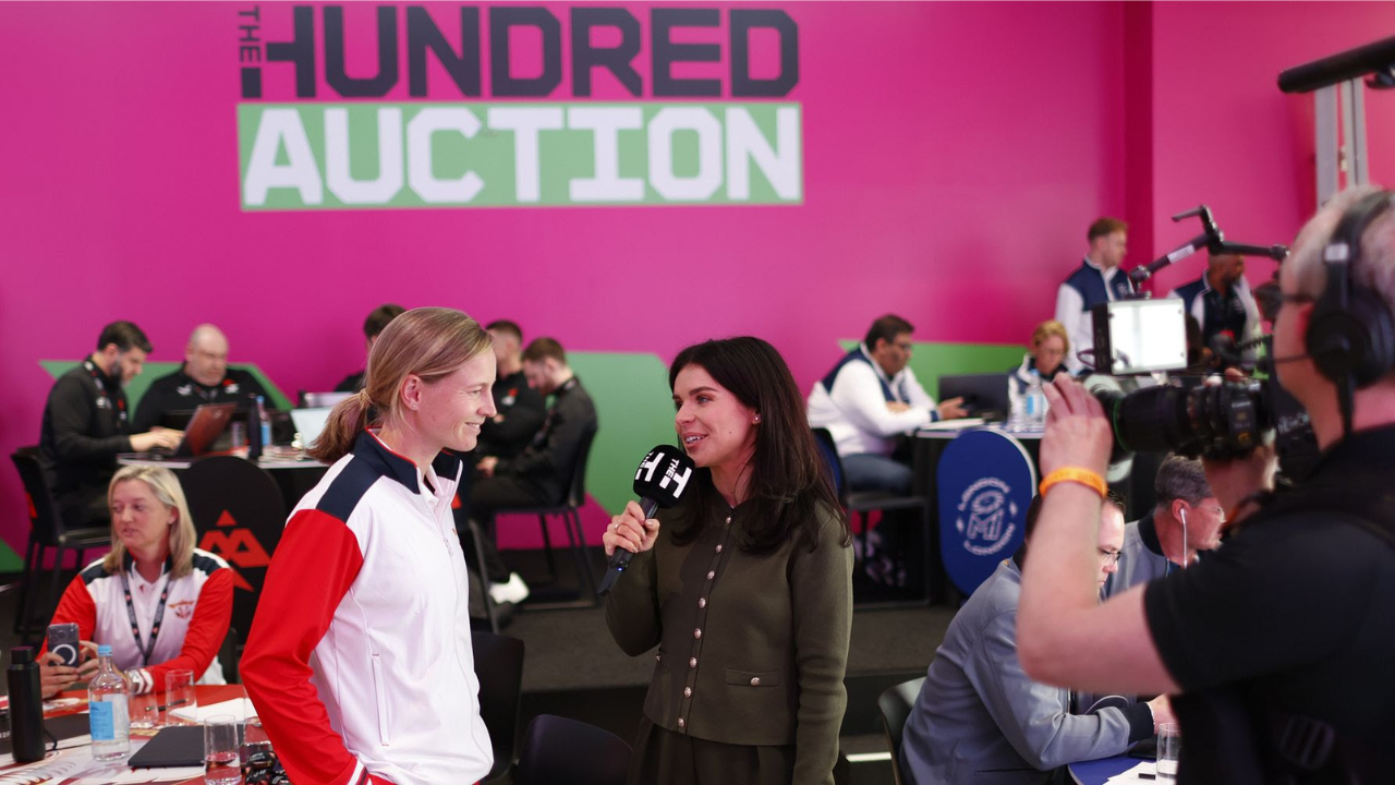 Meg Lanning being interviewed during The Hundred cricket auction with teams and media in the background.