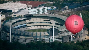 Aerial view of the Melbourne Cricket Ground (MCG) with a large red balloon promoting the 150th Anniversary Test match in Melbourne.
