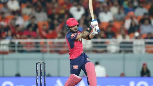 Riyan Parag playing an aggressive batting shot during an IPL match for Rajasthan Royals in a crowded stadium