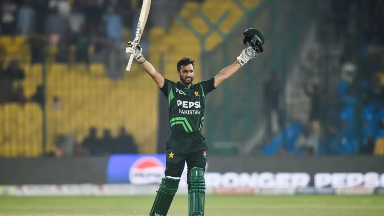 Salman Ali Agha celebrating his century with bat raised during a Pakistan cricket match in a stadium