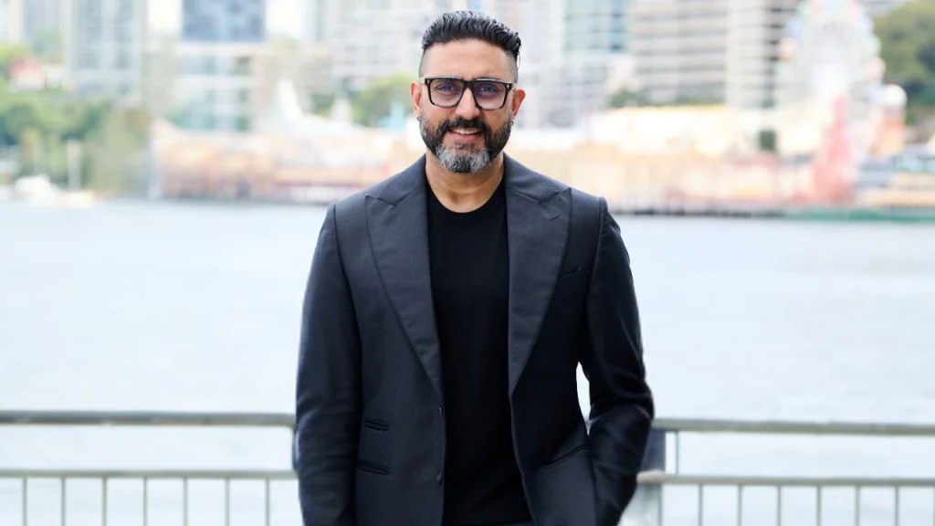 Abhishek Bachchan portrait with waterfront city background representing ETPL co-founder and cricket entrepreneur