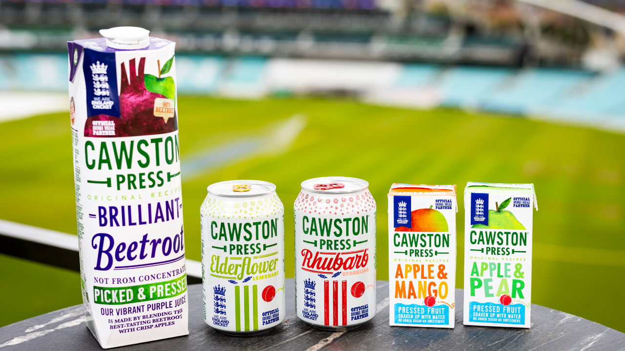 Cawston Press fruit drinks including beetroot juice, elderflower lemonade, rhubarb sparkling, apple mango, and apple pear displayed at a cricket ground.