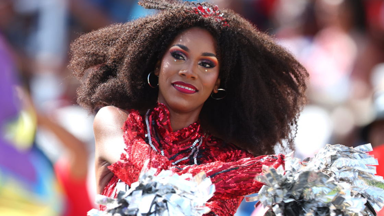 Cheerleader performing in red costume with pom-poms during Caribbean Premier League cricket match celebration